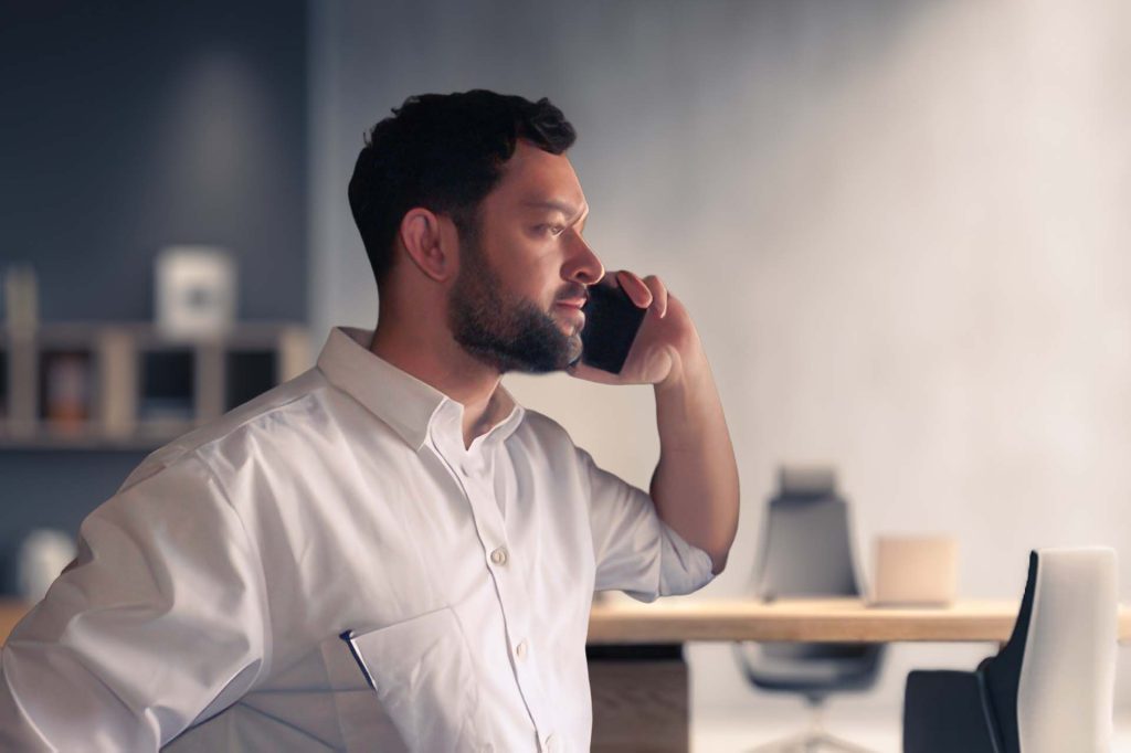 Andrew Mawson on cell phone in office.